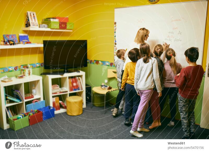 Teacher with students writing on whiteboard school schools blackboard blackboards write white board teacher instructor teachers pedagogue pedagogues education