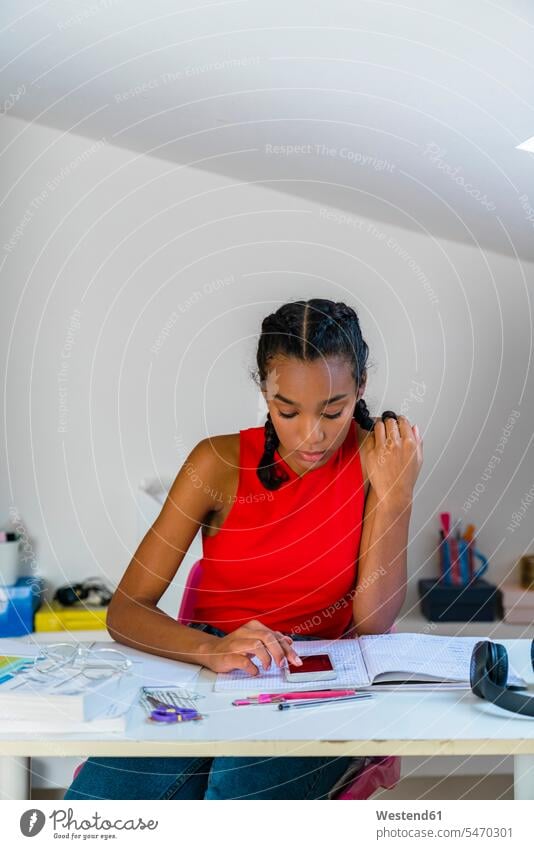 Teenage girl using smart phone while sitting on table at home color image colour image indoors indoor shot indoor shots interior interior view Interiors day