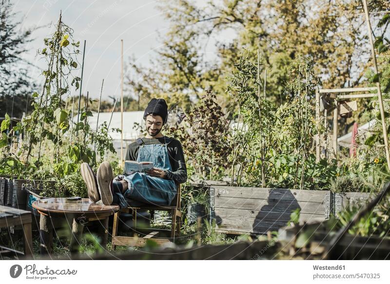 Smiling man reading book in urban garden books urbanity gardens domestic garden men males smiling smile urban scene outdoors outdoor shots location shot