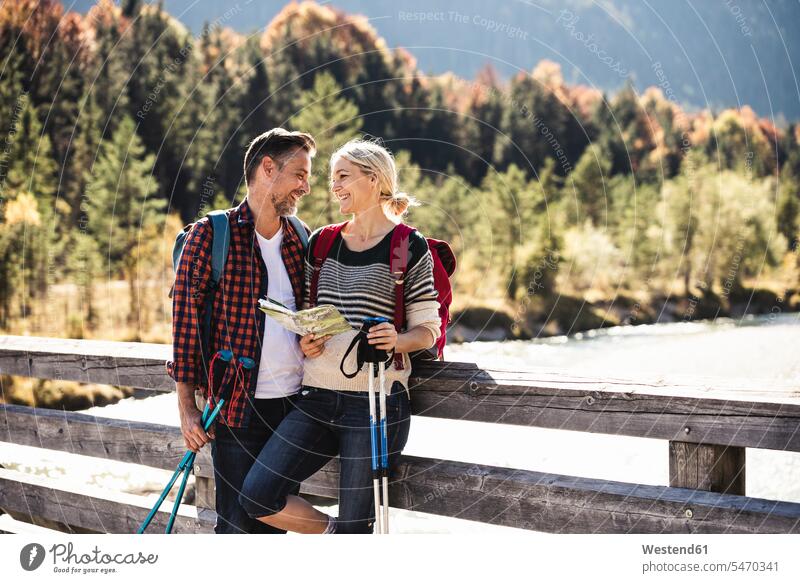 Austria, Alps, happy couple on a hiking trip with map on a bridge caucasian caucasian appearance caucasian ethnicity european White - Caucasian mature men