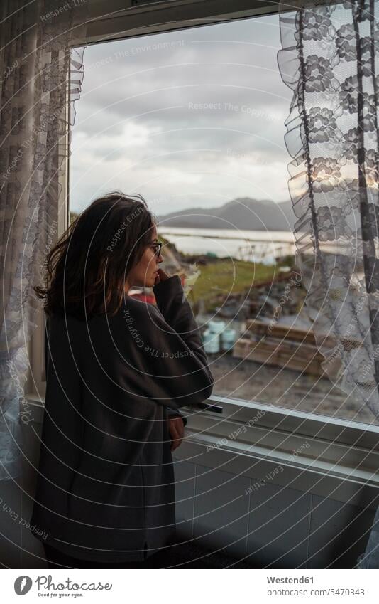 Young woman looking out of window standing windows Looking Through Window Looking Through A Window looking through glass young women young woman view seeing