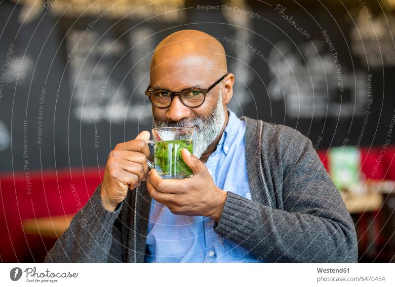 Portrait of smiling man with glass of tea in a coffee shop men males portrait portraits smile cafe Tea Teas Adults grown-ups grownups adult people persons