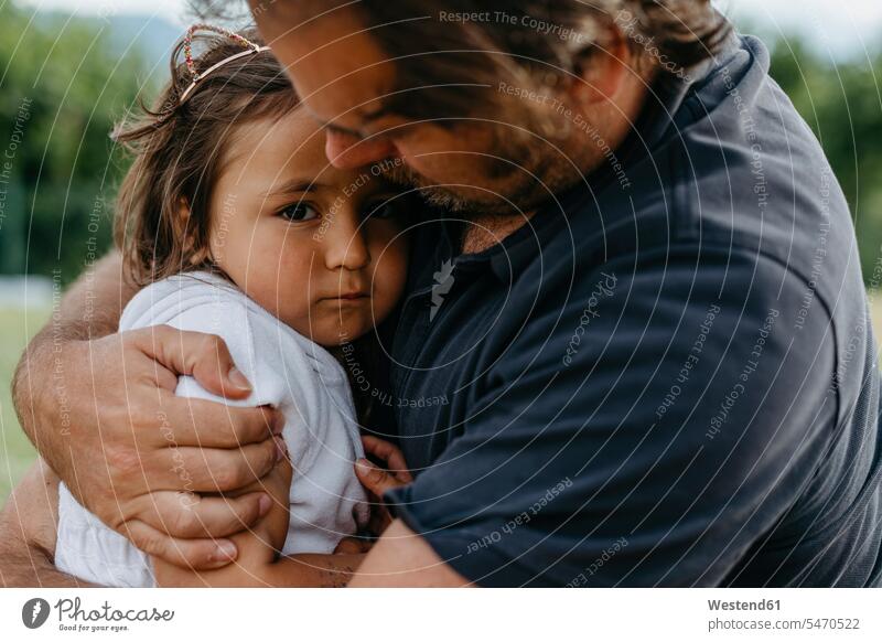 Father embracing daughter while sitting at backyard color image colour image outdoors location shots outdoor shot outdoor shots 2-3 years 2 to 3 years toddlers