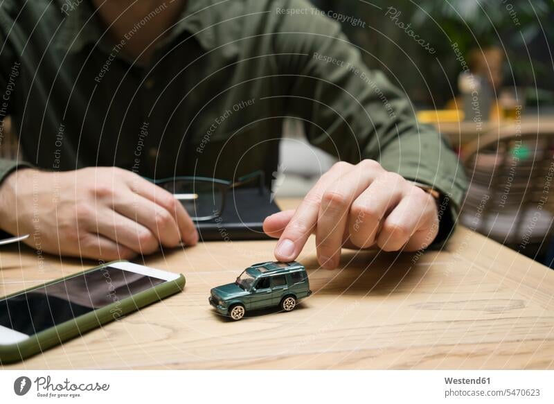 Businessman playing with toy car while sitting at cafe color image colour image day daylight shot daylight shots day shots daytime Businessmen Business man