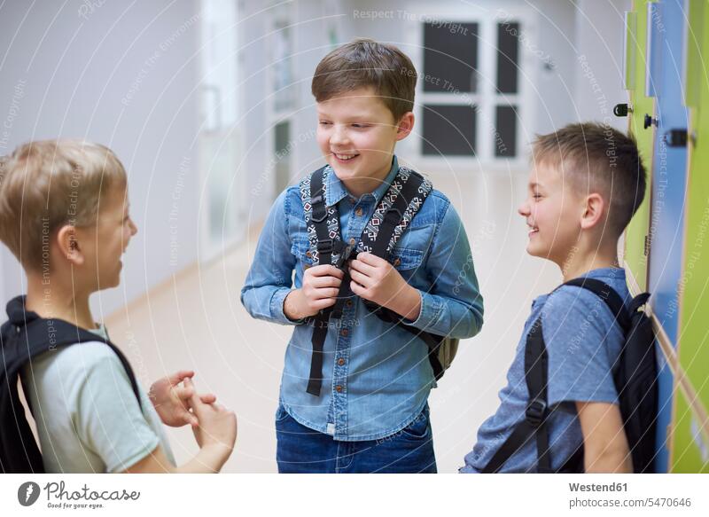 Happy pupils talking at lockers in school speaking happiness happy student schools boy boys males schoolchildren education kid kids people persons human being