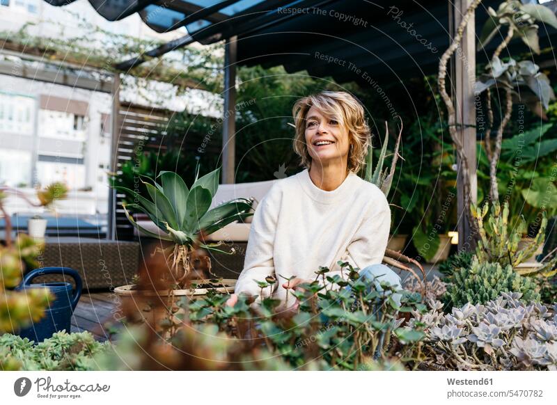 Smiling woman looking away amidst plant at rooftop garden color image colour image outdoors location shots outdoor shot outdoor shots day daylight shot