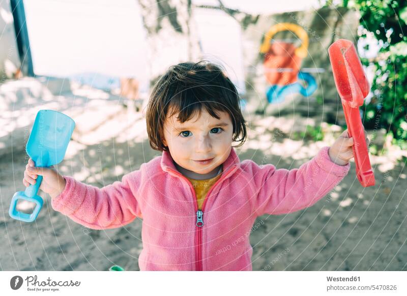 Baby girl playing with sand and shovels outdoors sandbox sandpits sand-box sandboxes sand-boxes carefree toy toys smiling smile baby girls female babies infants