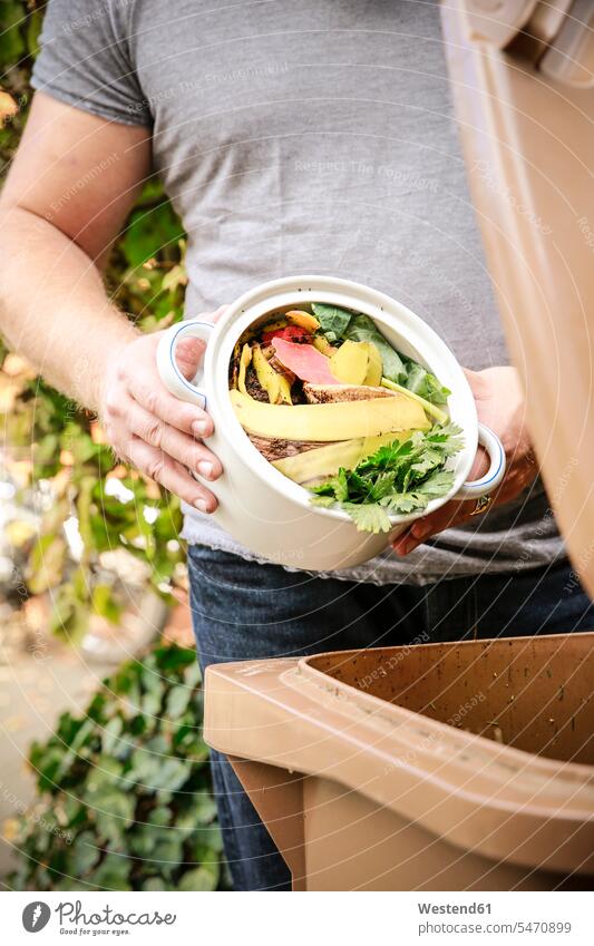 Mature man throwing kitchen scraps into bio-waste container kitchen waste garden gardens domestic garden mature men mature man males Adults grown-ups grownups