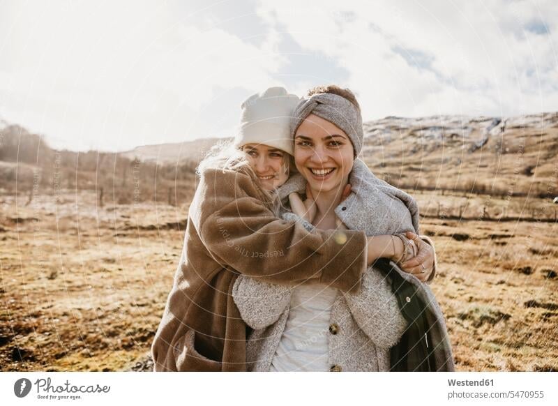 UK, Scotland, happy female friends hugging in rural landscape landscapes scenery terrain portrait portraits happiness woman females women embracing embrace