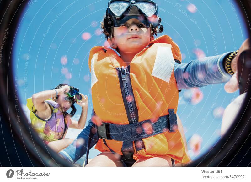 Toddler wearing life jacket and diving goggles with brother in background brothers life jackets Lifejacket life vests boy boys males siblings brother and sister