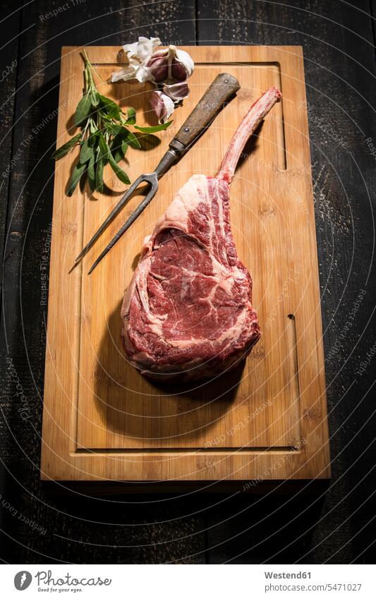 Raw tomahawk steak, garlic and herbs meat fork Garlic Bulb Garlic Bulbs Garlic Tuber ingredient ingredients culinary herb culinary herbs kitchen herb