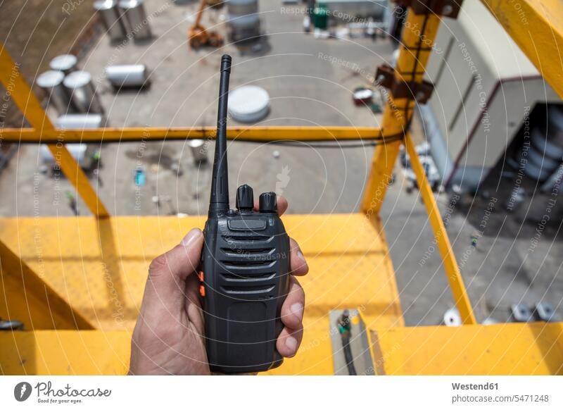 Hand holding walkie talkie on top of a crane on construction site walkie-talkie walkie-talkies walkie talkies two-way radios cranes construction machine