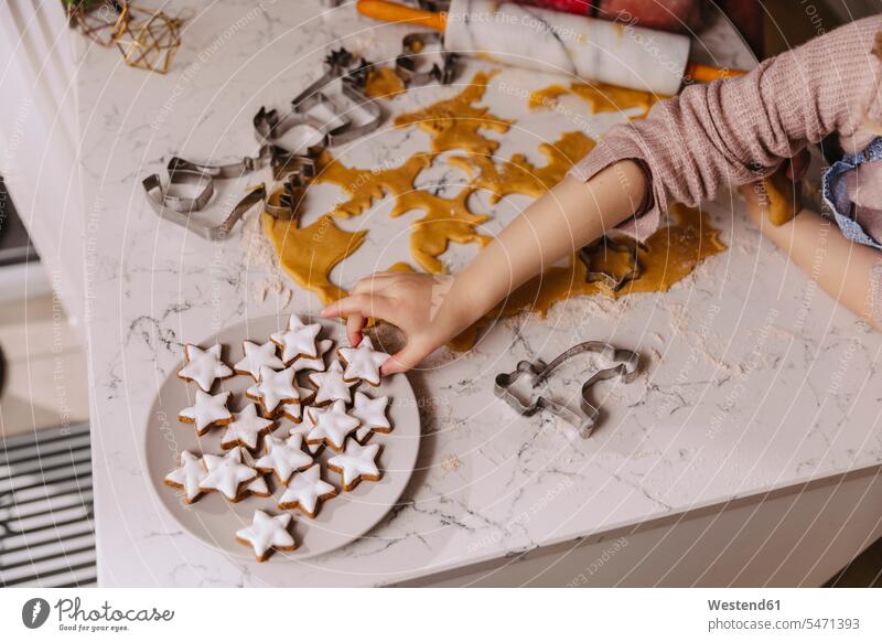 Close-up of girl taking Christmas cookie from plate on kitchencounter dish dishes Plates bake shapes star Star Shaped Star Shapes star-shaped stars at home