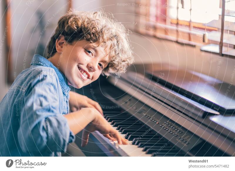 Portrait of smiling boy playing piano at home human human being human beings humans person persons curl curled curls curly hair Instrument Instruments
