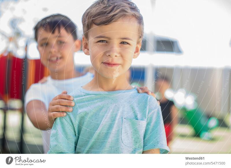 Portrait of smiling boy with friends on playground in kindergarten play yard play ground playgrounds mate boys males portrait portraits smile nursery school