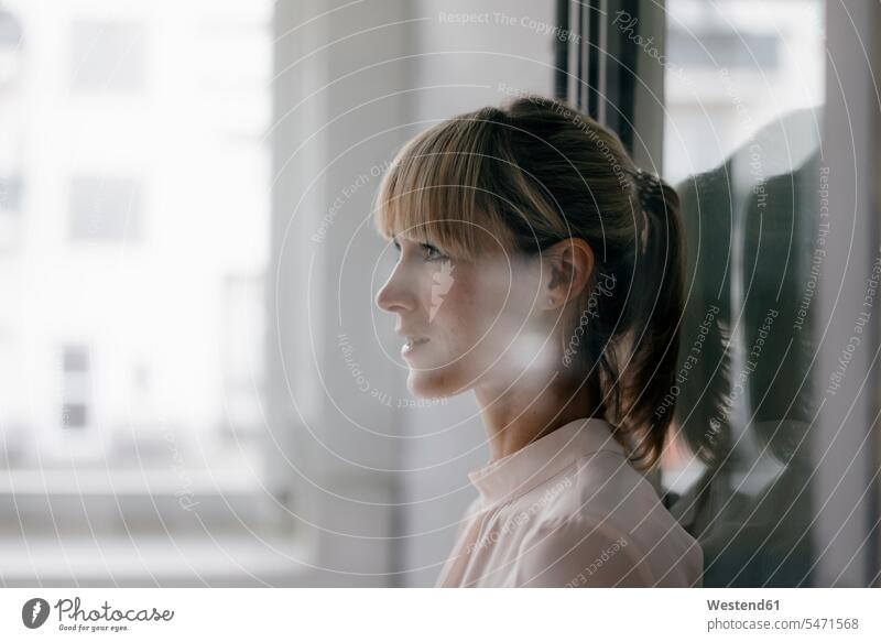 Portrait of a businesswoman leaning on glass pane profile Profile View profiles businesswomen business woman business women window windows smiling smile