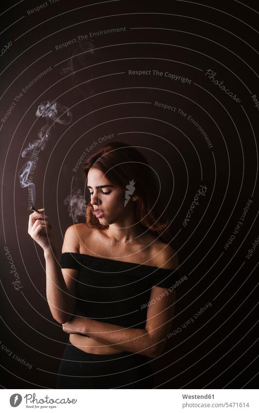 Young woman smoking marihuana at home tobacco Tobacco Products cigarettes smoke Seated sit in the evening relax relaxing relaxation enjoy enjoyment indulgence