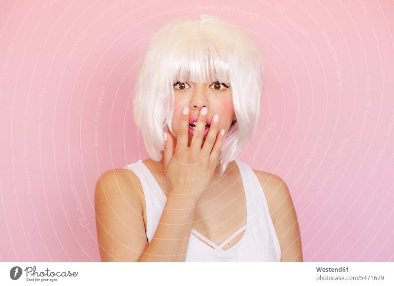 Portrait of frightened young woman with hand covering mouth in front of pink background colour colours Rosy Distinct individual stylish Lifestyle Lipsticks