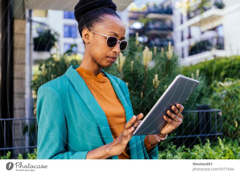 Portrait of young businesswoman wearing sunglasses using digital tablet outdoors business life business world business person businesspeople business woman