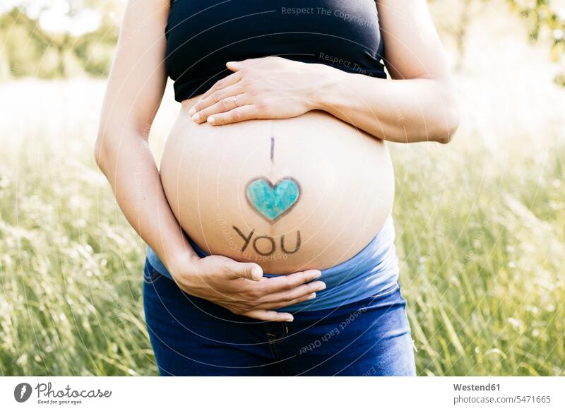 Young pregnant woman holding baby belly, I love you upper part of the body bellies stomach stomachs touch Emotions Feeling Feelings Sentiment Sentiments loving