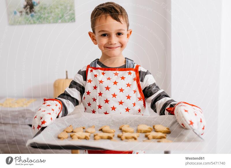 Portrait of smiling little boy holding baking tray with home-made cookies portrait portraits smile Biscuit Cookie Cooky Cookies Biscuits baking trays home-baked