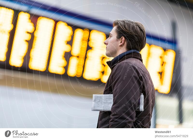 UK, London, businessman at train station looking at timetable schedule watching Businessman Business man Businessmen Business men view seeing viewing