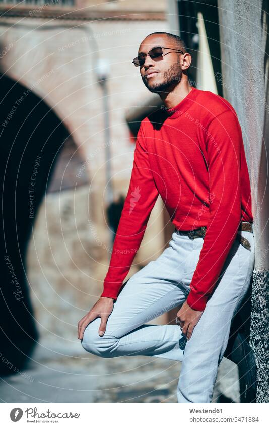 Portrait of fashionable young man wearing red pullover and socks enjoying sunlight sweater jumper Sweaters indulgence enjoyment savoring indulging portrait