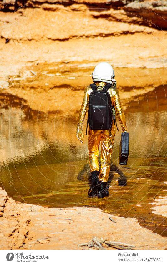 Astronaut standing while exploring on moon color image colour image outdoors location shots outdoor shot outdoor shots rear view back view view from the back