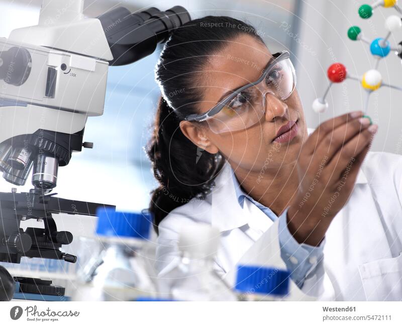 Biotechnology Research, female scientist examining a chemical formula using a ball and stick molecular model in the laboratory researcher research scientist