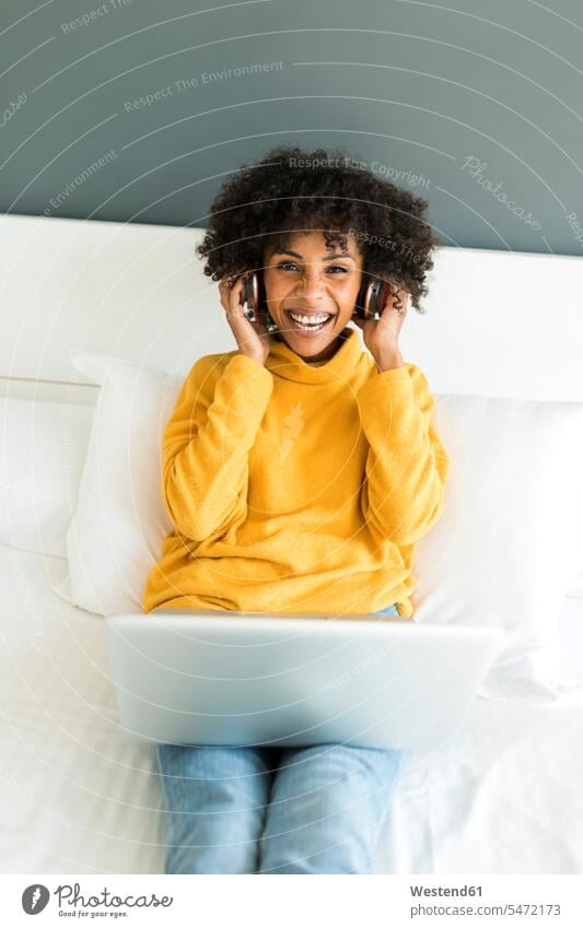 Portrait of happy woman lying on bed with headphones and laptop happiness Laptop Computers laptops notebook beds headset laying down lie lying down females