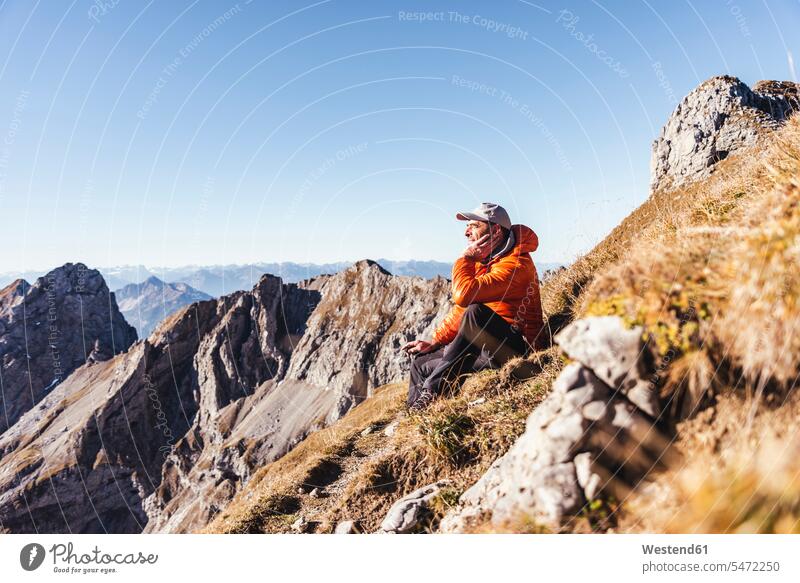 Male hiker contemplating while sitting on mountain against clear sky during sunny day color image colour image Austria leisure activity leisure activities