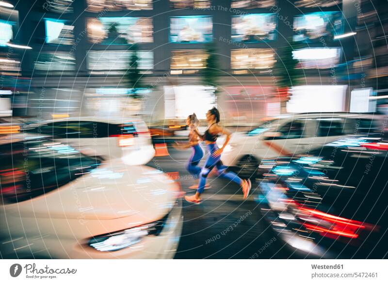 Long exposure photo of two women running through the streets in the city at night friends mate female friend motor vehicles road vehicle road vehicles Auto