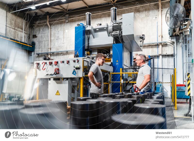 Young male engineer listening to mature coworker during meeting in industry color image colour image indoors indoor shot indoor shots interior interior view