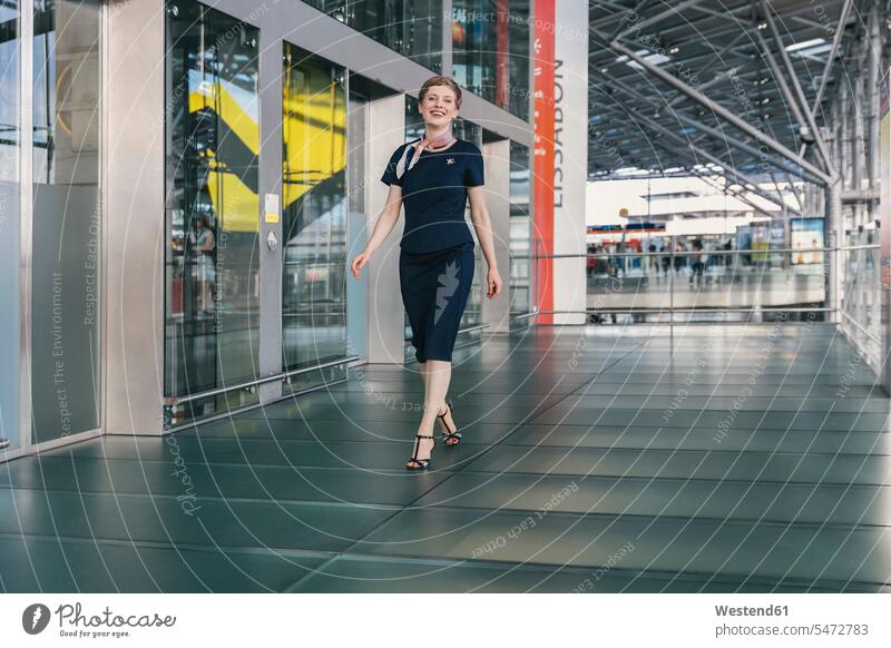 Portrait of smiling airline employee walking at the airport stewardess air hostess stewardesses woman females women airports smile portrait portraits employess