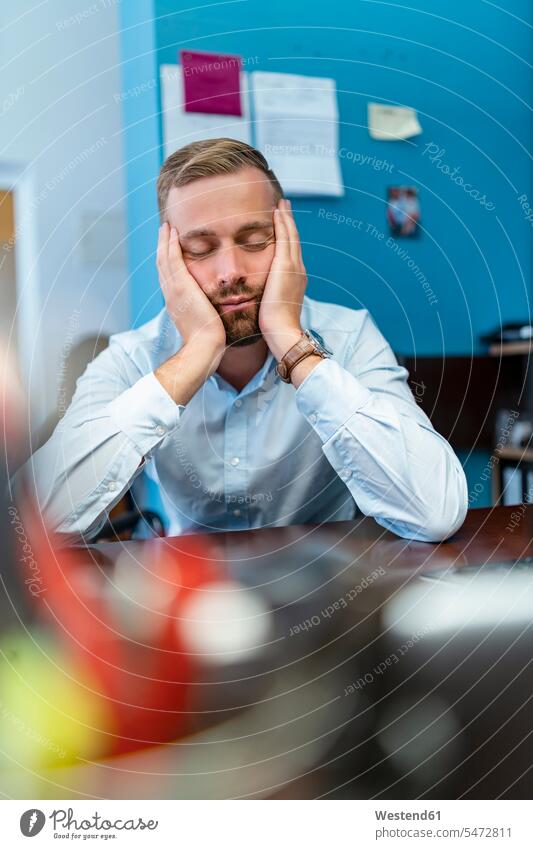 Tired businessman with closed eyes leaning on desk in office human human being human beings humans person persons caucasian appearance caucasian ethnicity