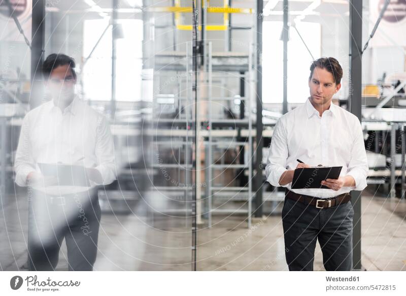 Man with clipboard taking notes in modern factory factories clipboards clip-board clip-boards clip board contemporary man men males making a note note taking