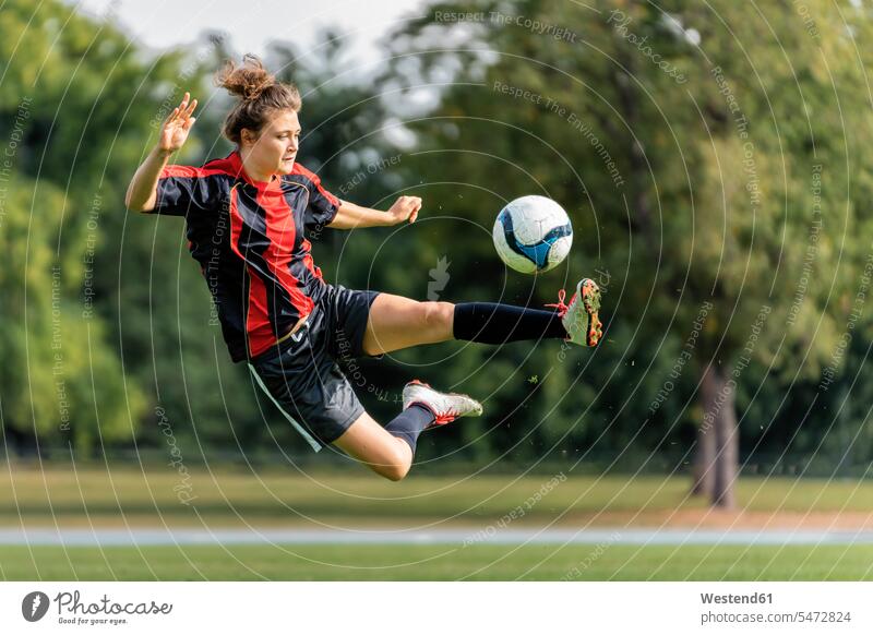 Young woman playing soccer in field color image colour image Germany outdoors location shots outdoor shot outdoor shots day daylight shot daylight shots