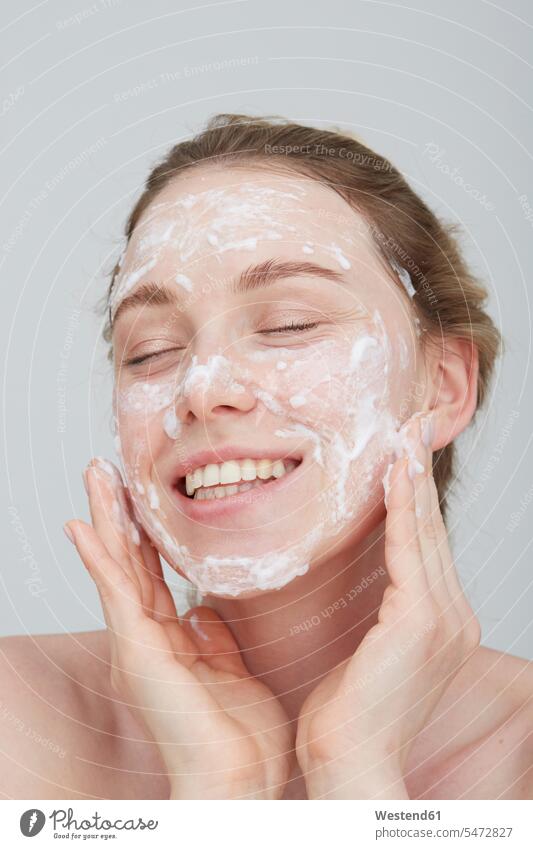 Portrait of blond young woman with eyes closed applying cream on her face human human being human beings humans person persons caucasian appearance