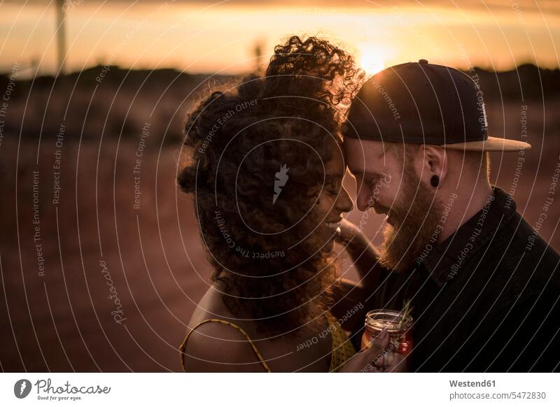 Happy couple with fresh ice tea drink outdoors at sunset touristic tourists human human being human beings humans person persons curl curled curls curly hair