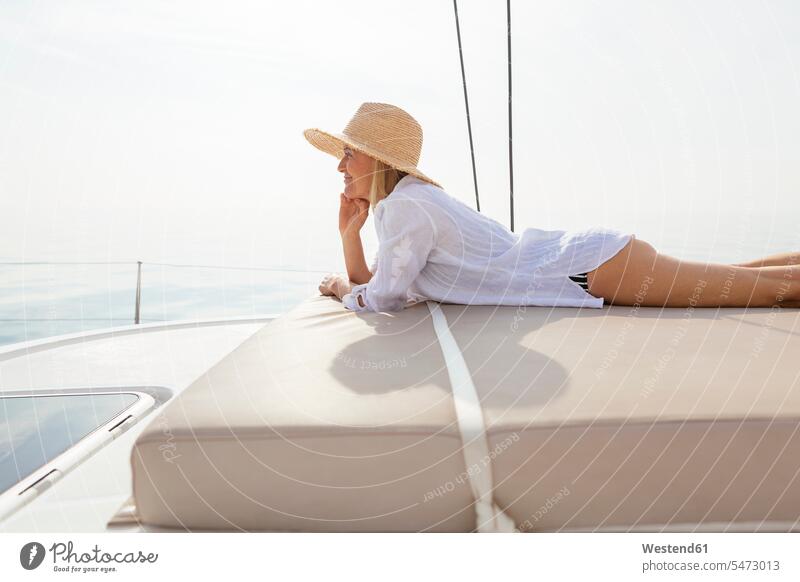 Mature woman relaxing on a catamaran, taking a sunbath mature woman mature women deck sunbathing sun bath Sun Bathing basking Sunbath sun-bath sunbathe Mattress