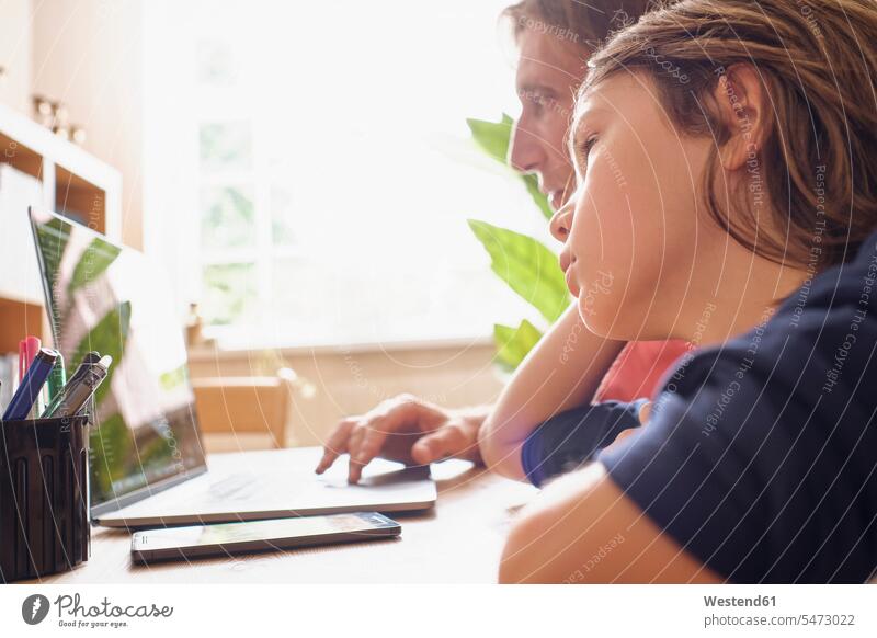 Father and son using laptop while doing studying at home color image colour image indoors indoor shot indoor shots interior interior view Interiors day