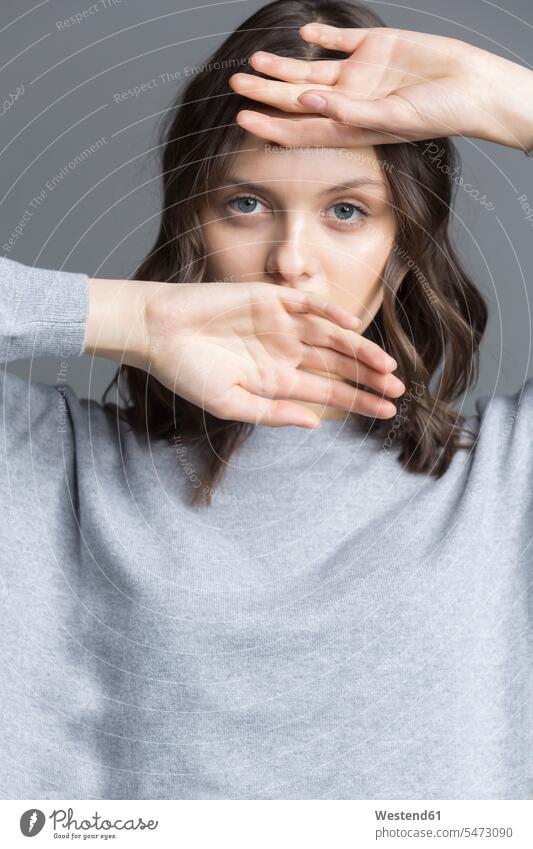 Portrait of brunette young woman, hands over her face portrait portraits obscured face obscured faces face hidden shy shyness Coy hiding obscuring brown hair