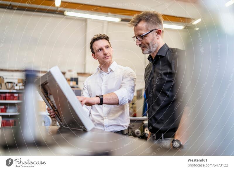 Two colleagues in factory working on solar cell man men males factories solar panels solar cells At Work Adults grown-ups grownups adult people persons