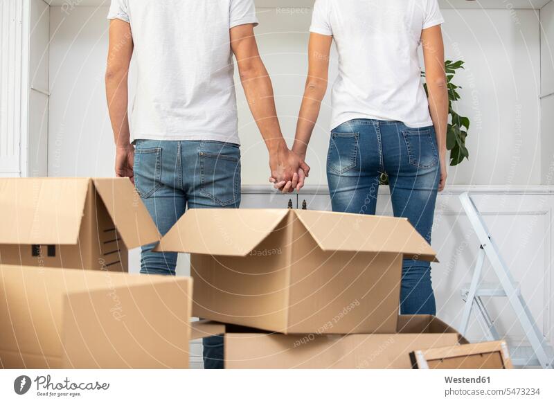 Close-up of couple with cardboard boxes standing hand in hand in new home Cardboard Carton carton Cardboards cartons apartment flats apartments at home