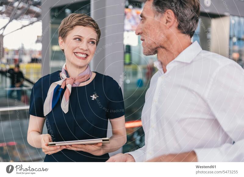 Happy airline employee with tablet talking to passenger at the airport employess passengers digitizer Tablet Computer Tablet PC Tablet Computers iPad