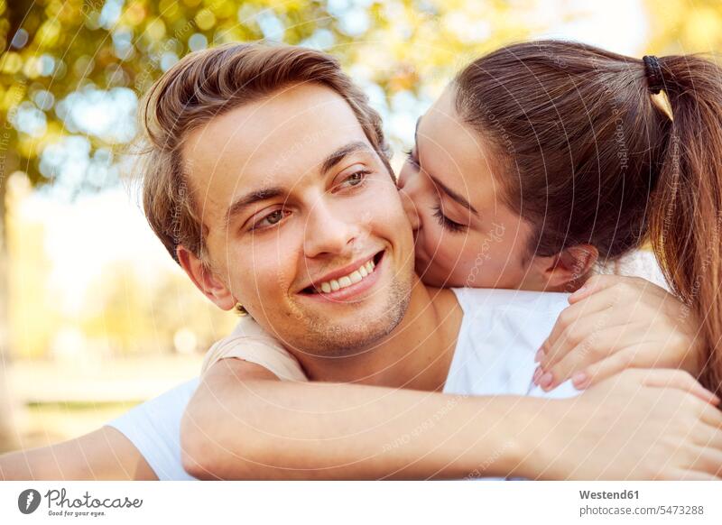 Happy young couple in love kissing at a park kisses twosomes partnership couples parks happiness happy people persons human being humans human beings confidence