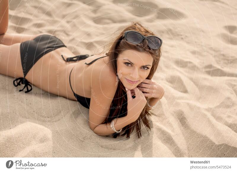 Beautiful young woman lying on sand at beach color image colour image outdoors location shots outdoor shot outdoor shots day daylight shot daylight shots