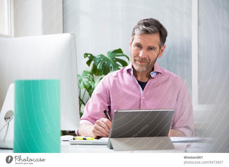 Portrait of a man working at desk in office portrait portraits men males desks At Work offices office room office rooms Adults grown-ups grownups adult people