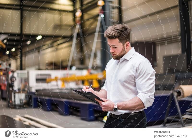 Man writing on clipboard on factory shop floor man men males write clipboards clip-board clip-boards clip board factories production hall Adults grown-ups