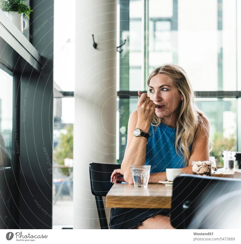 Young woman in cafe, drinking coffee and eating sweets nibbling snacking nibble young women young woman pretty Prettiness Dessert Afters Desserts sitting Seated